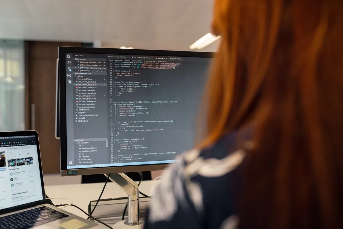 Engineer working at a computer with dual monitors in a workshop