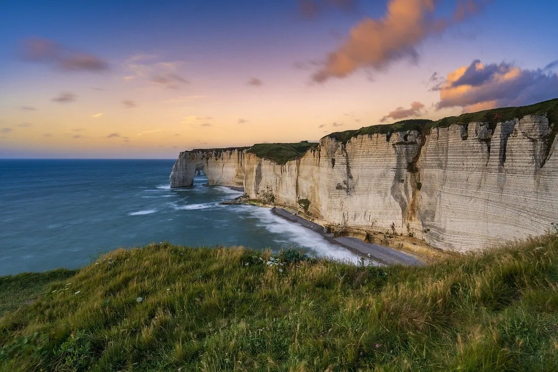 Cliff coastline with ocean waves and green hills
