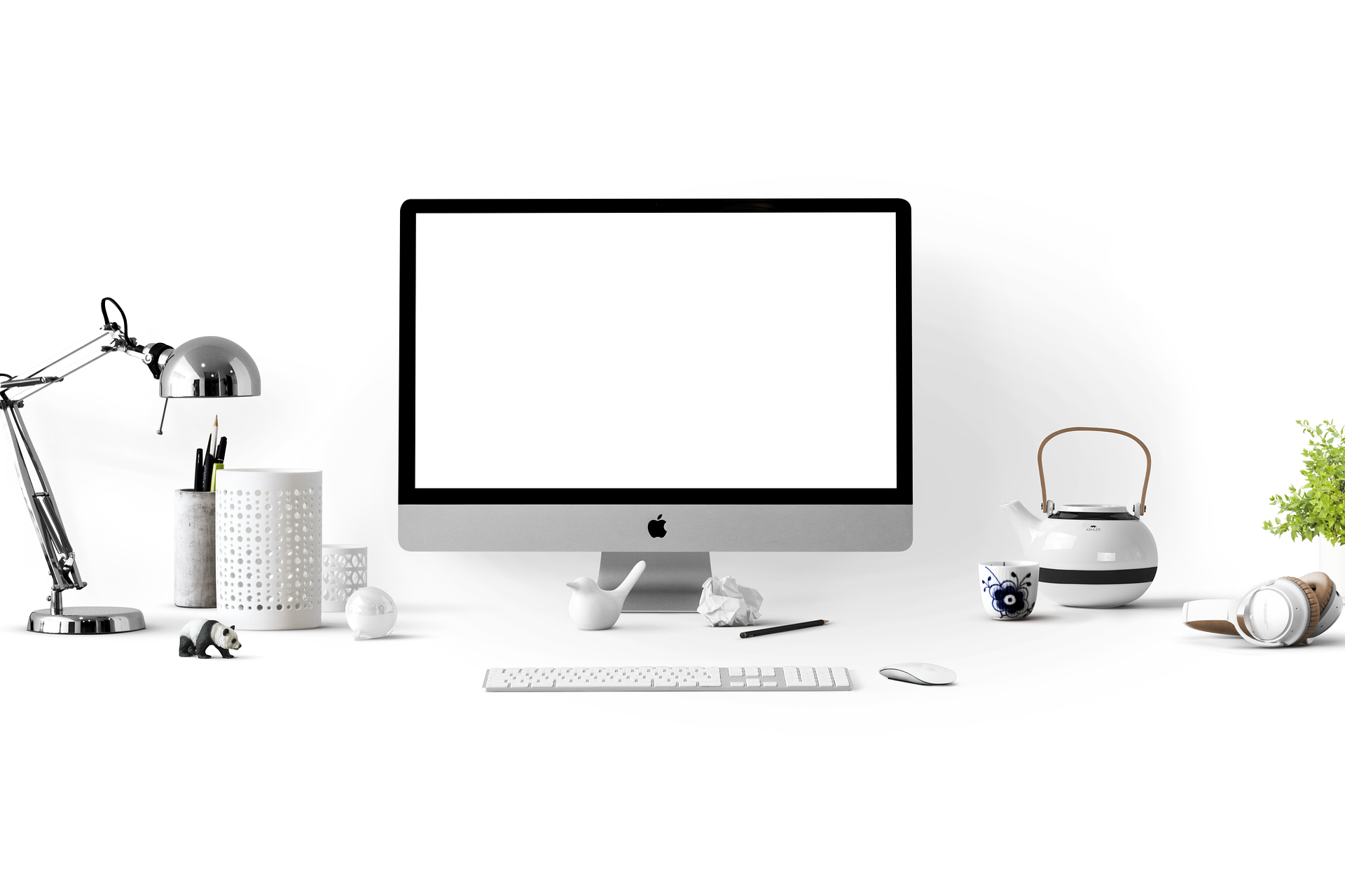 A clean white desk with an iMac computer, keyboard, mouse, desk lamp, and small decorative items