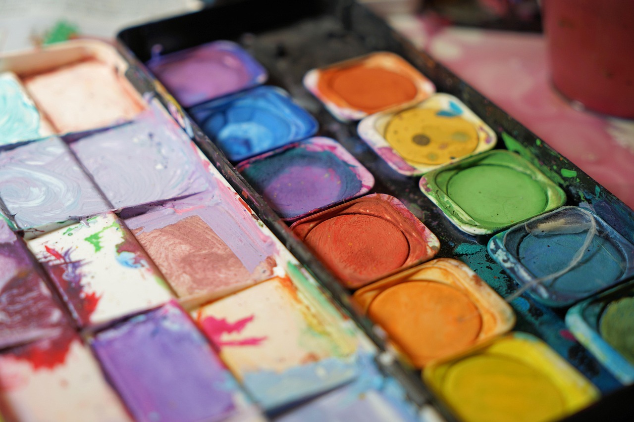 Close-up of a well-used watercolor paint palette with mixed colors in each well