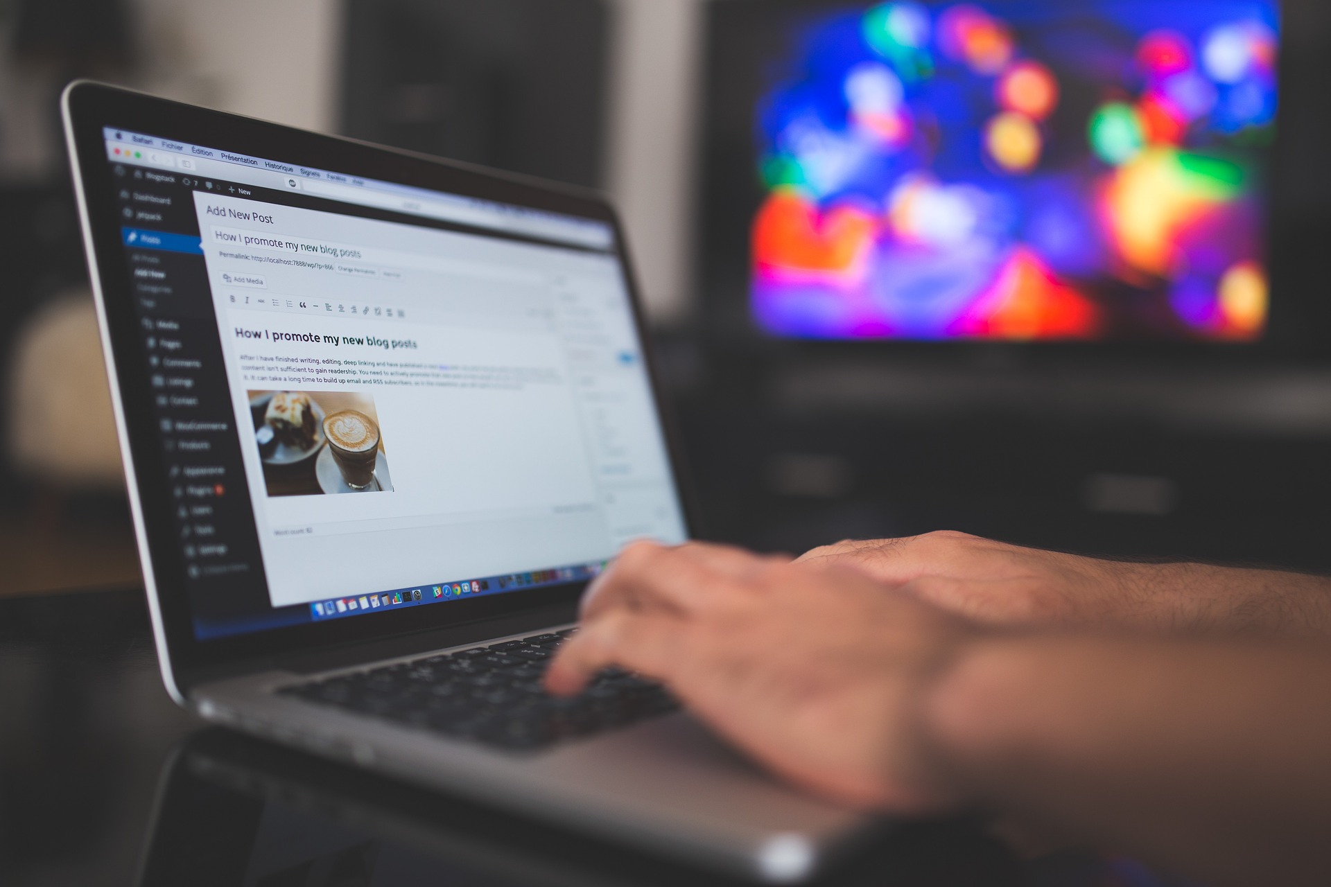 Person typing on a laptop showing a website admin panel interface, with colorful bokeh lights in the background