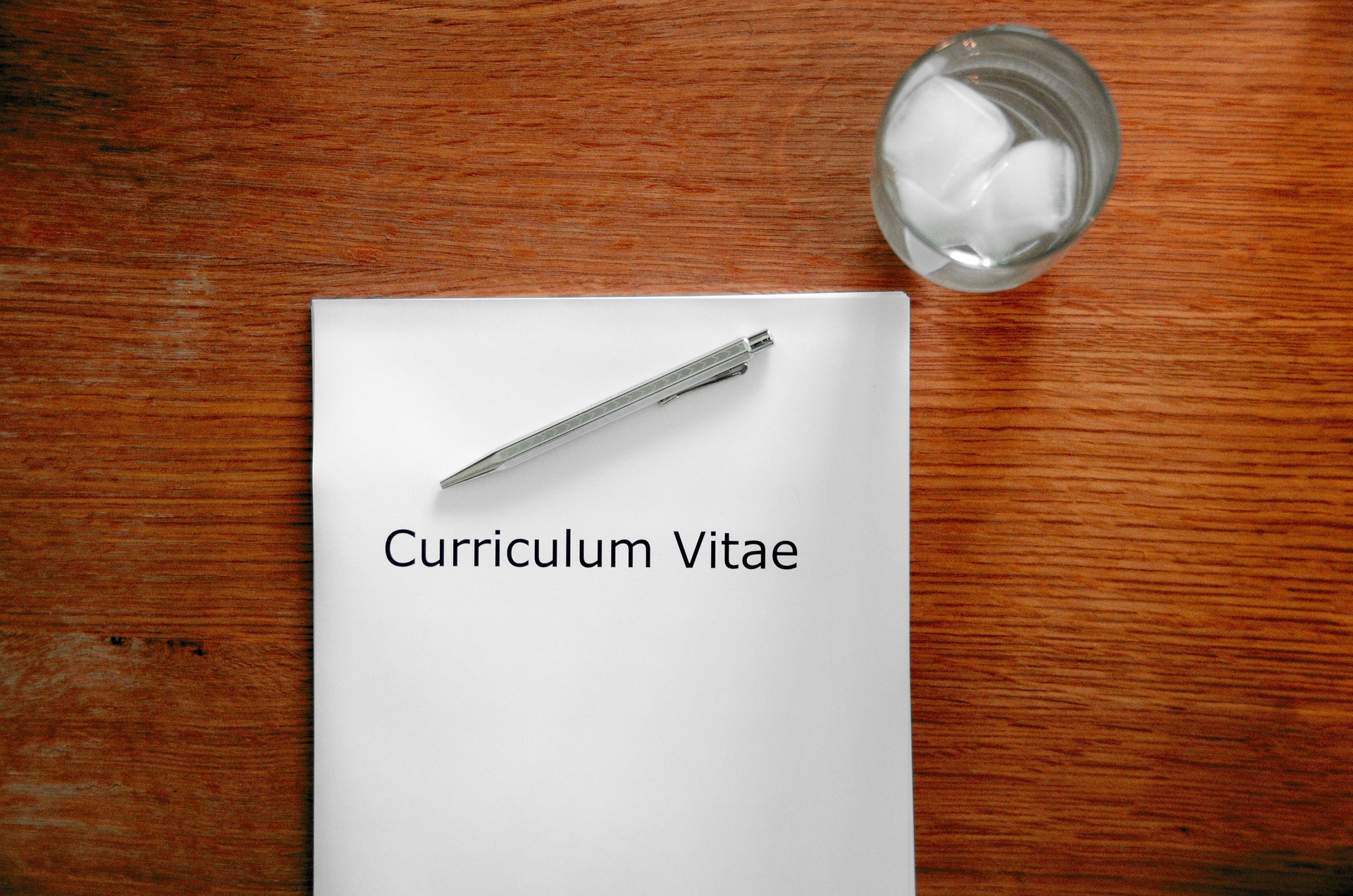 Job application documents and curriculum vitae on a desk with pen