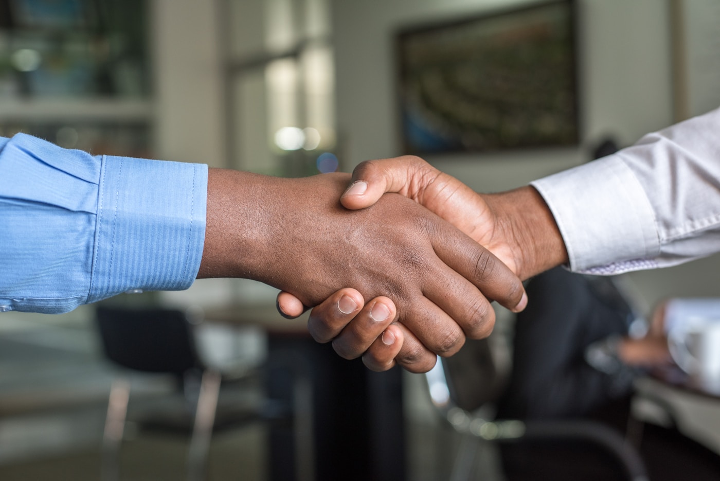 Two professionals shaking hands across a desk in an office setting
