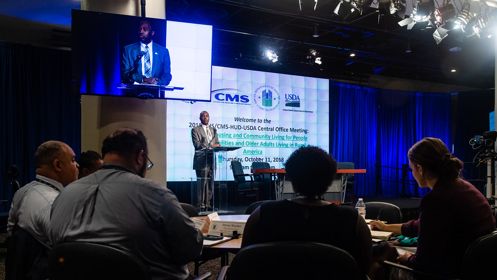 Large conference room with rows of tables and attendees during a group office meeting