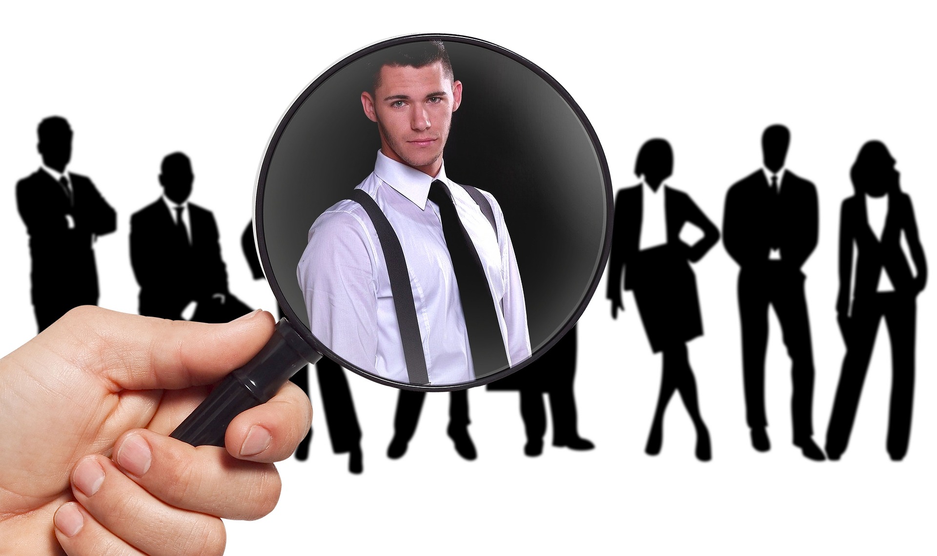 A magnifying glass held over a group of silhouetted business people, focusing on one candidate in a white shirt